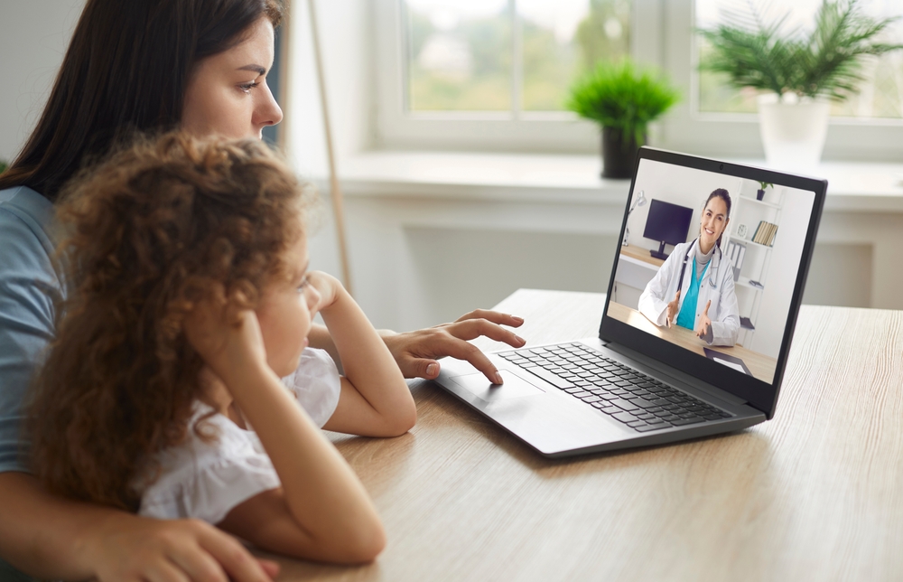 Mother and child using a laptop for a virtual doctor appointment, highlighting the importance of secure telehealth and virtual care cybersecurity to protect patient data.